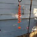 Orange crochet spiral wind spinner with a green center and a small orange pumpkin hanging at the bottom.