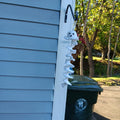 White crochet ghost wind spinner with black facial details and a white spiral hanging below.