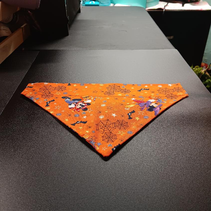 Small Halloween pet bandana in an orange print with wizard characters, stars, spider webs, and bats